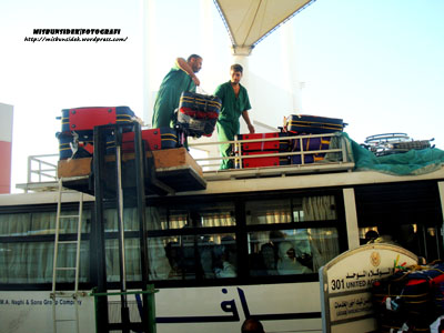 Para pekerja haji sedang memunggah beg-beg dan kelengkapan ke atas bumbung bas sebelum bertolak ke Mina.